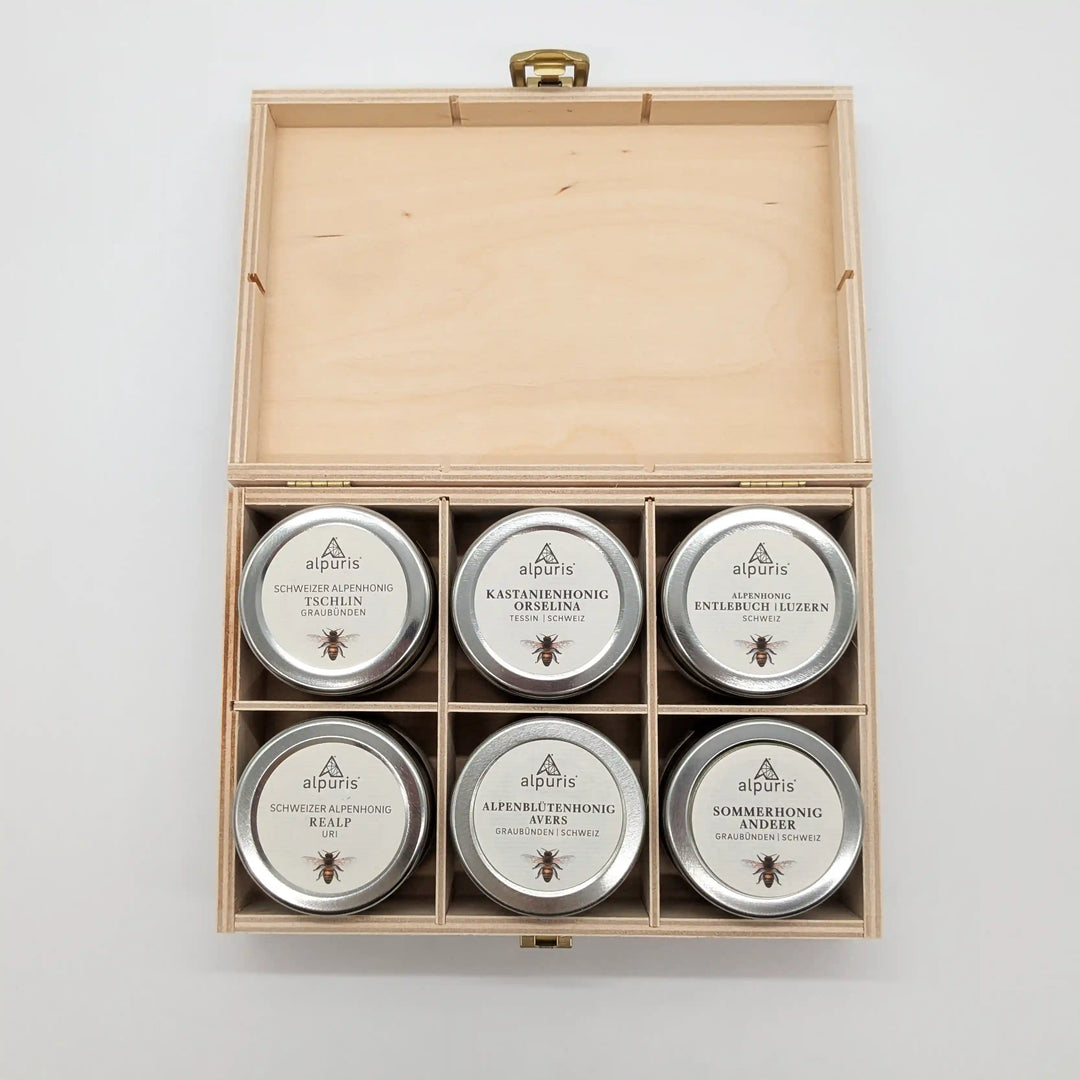 Sechs Alpenhonige von Alpuris in der Holzbox mit traditionellem Scherenschnitt-Motiv. Bei www.bio-vivo.ch bestellen.