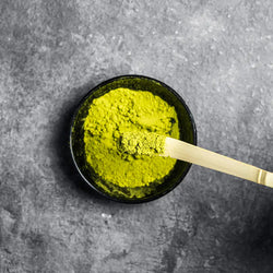 Bio Matcha-Pulver mit Messlöffel in schwarzer Schale zum Dosieren
