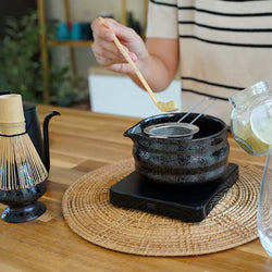 Matcha-Pulver wird mit Teelöffel in traditionelle japanische Schale mit Sieb dosiert